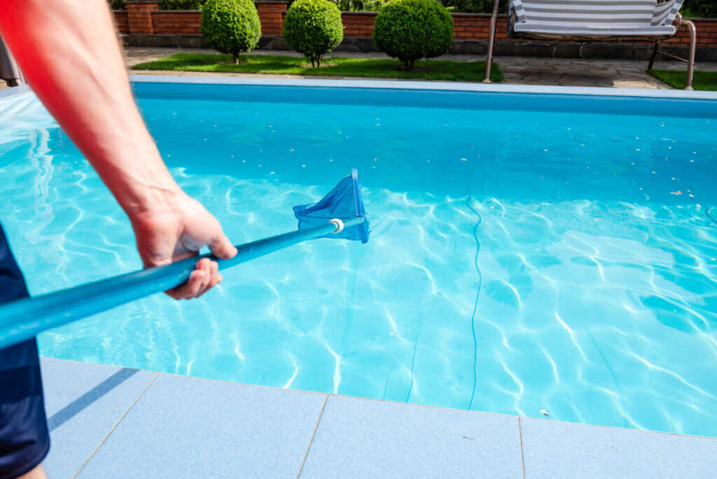 Pool service technician cleaning a residential swimming pool